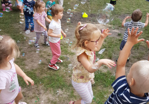 Dzieci próbujące złapać banieczki mydlane.